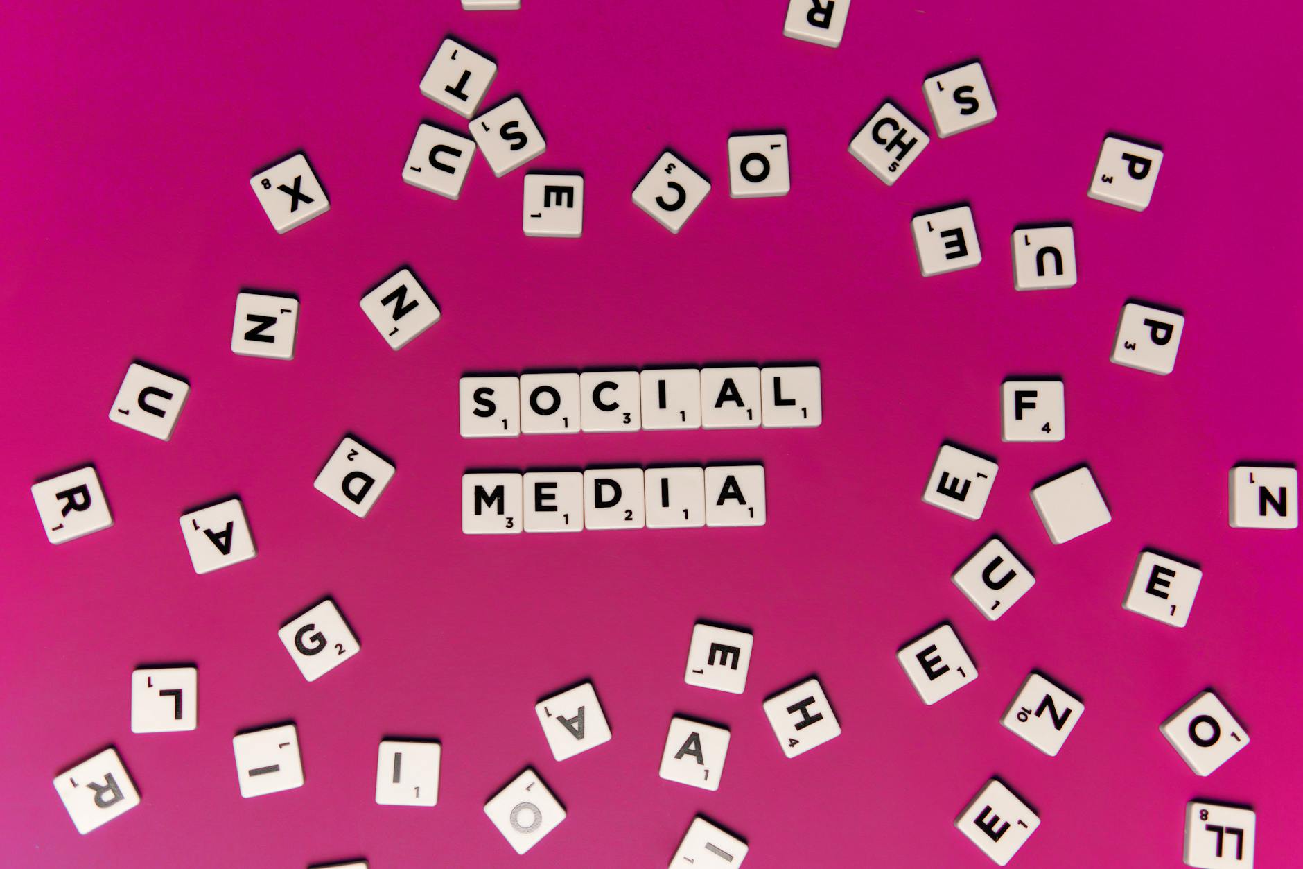 Scrabble tiles strewn across a brightly coloured surface. The centre tiles are brought together to read 'social media'.