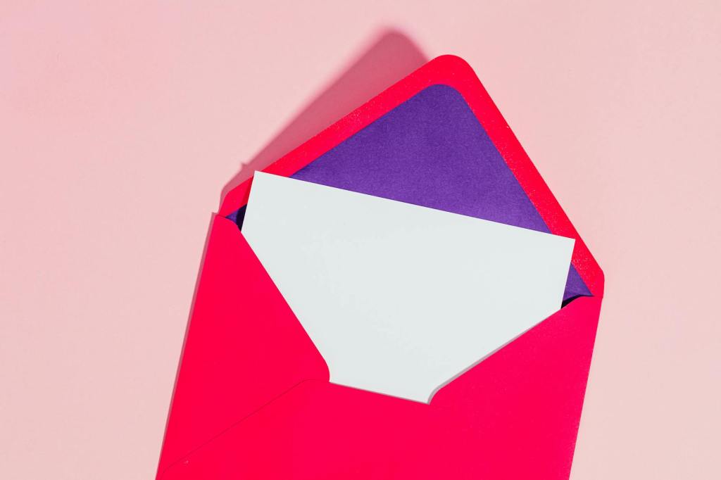 A brightly coloured envelope sits open, with a black piece of paper or card protruding from inside.